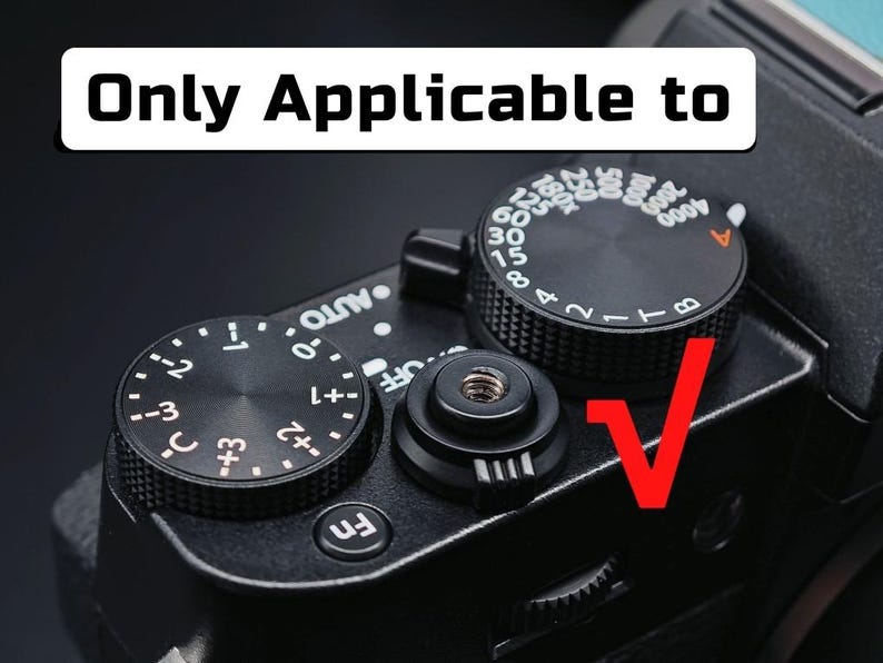 May include: A black camera top plate featuring a shutter button, a function button, and two circular control dials with white markings. One dial displays exposure compensation values, while the other shows shutter speeds. Text reads Only Applicable to.