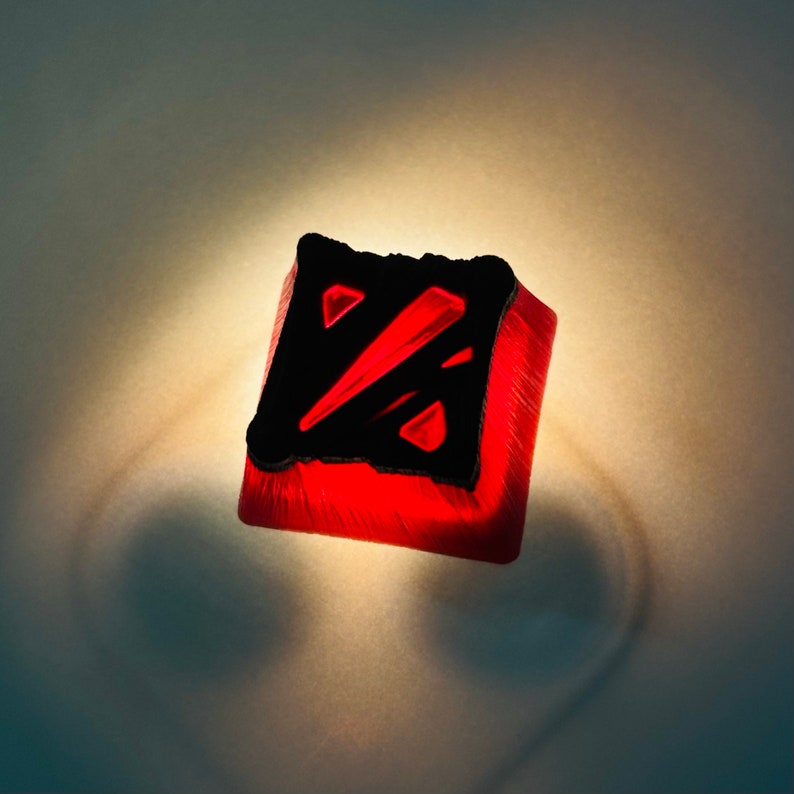 May include: A red and black keycap with a stylized "Z" logo. The keycap is made of a translucent material and has a glossy finish.