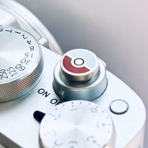 May include: A silver camera with a red and blue button. The camera has a dial with numbers and the words "ON OFF" printed on it.