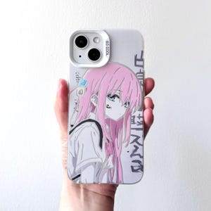 Puede incluir: Una funda blanca para iPhone con una ilustración de estilo anime de una chica con pelo rosa y ojos azules. La funda tiene texto japonés y las palabras "SO COOL" impresas.