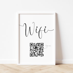 Puede incluir: Una impresi&oacute;n enmarcada en blanco con la palabra "Wifi" en escritura cursiva y un c&oacute;digo QR en blanco y negro con el texto "Scan me!" al lado.