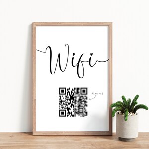 Puede incluir: Una impresi&oacute;n enmarcada con la palabra "Wifi" en cursiva con un coraz&oacute;n sobre la "i". Debajo de la palabra hay un c&oacute;digo QR en blanco y negro con una flecha que apunta a &eacute;l y el texto "&iexcl;Escaneame!"