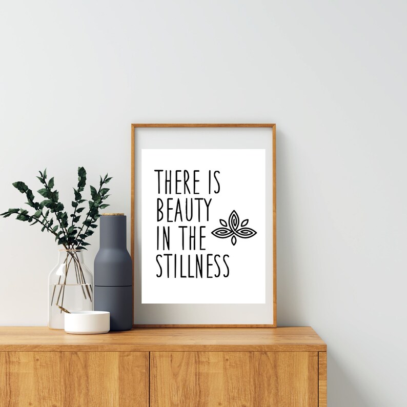 Puede incluir: Una impresi&oacute;n enmarcada con un dise&ntilde;o en blanco y negro. La impresi&oacute;n presenta el texto "THERE IS BEAUTY IN THE STILLNESS" y una flor de loto estilizada.
