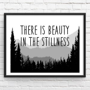 May include: Black and white print with a quote that reads "There is beauty in the stillness." The quote is set against a silhouette of a mountain range with trees.