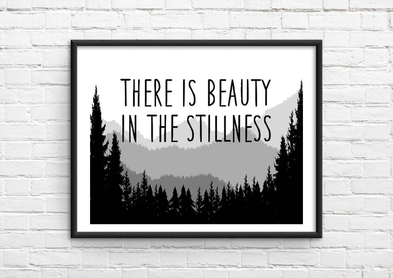 May include: Black and white print with a quote that reads "There is beauty in the stillness." The quote is set against a silhouette of a mountain range with trees.