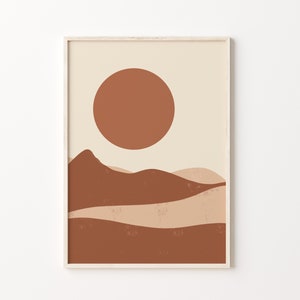 May include: Abstract art print featuring a minimalist landscape with a large, rust-colored sun and layered, earthy-toned hills. The artwork is framed in a light wood frame, creating a warm and inviting aesthetic. The color palette includes shades of beige, brown, and rust.
