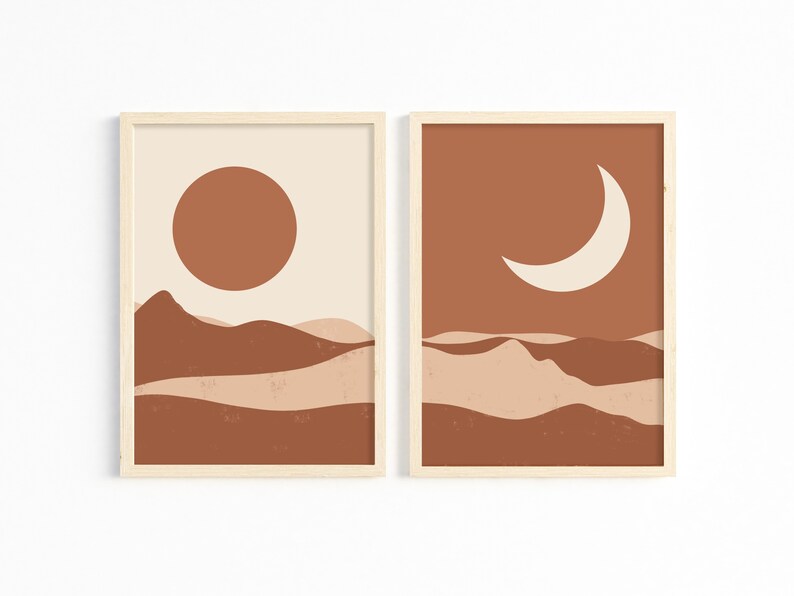 May include: Two framed art prints with a minimalist desert landscape theme. One features a rust-colored sun over brown and beige hills against a cream background. The other shows a cream crescent moon over similar hills against a rust background.