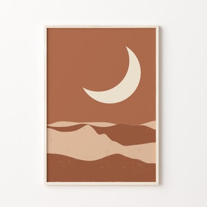 May include: Abstract art print featuring a crescent moon and desert landscape in shades of brown and beige. The artwork is framed in a light wood frame, suitable for home decor.