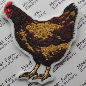 May include: An embroidered patch of a chicken, featuring brown and gold stitching. The patch is on a white background with the text "Moat Farm Embroidery" written on it.