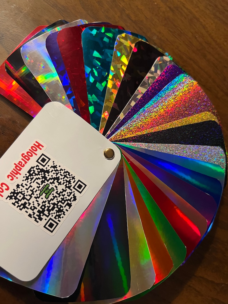 Może przedstawiać: Wzornik kolor&oacute;w w kształcie wachlarza z holograficznych arkuszy winylowych. Wzornik jest oznaczony jako "Holographic Co.".