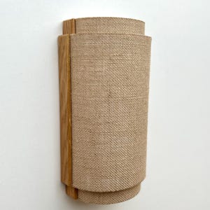 May include: A wall-mounted light fixture with a natural wood frame and a beige linen shade.