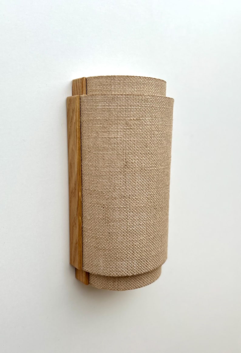 May include: A wall-mounted light fixture with a natural wood frame and a beige linen shade.