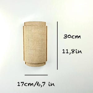 May include: A beige wall sconce with a woven fabric shade. The sconce measures 11.8 inches tall and 6.7 inches wide.
