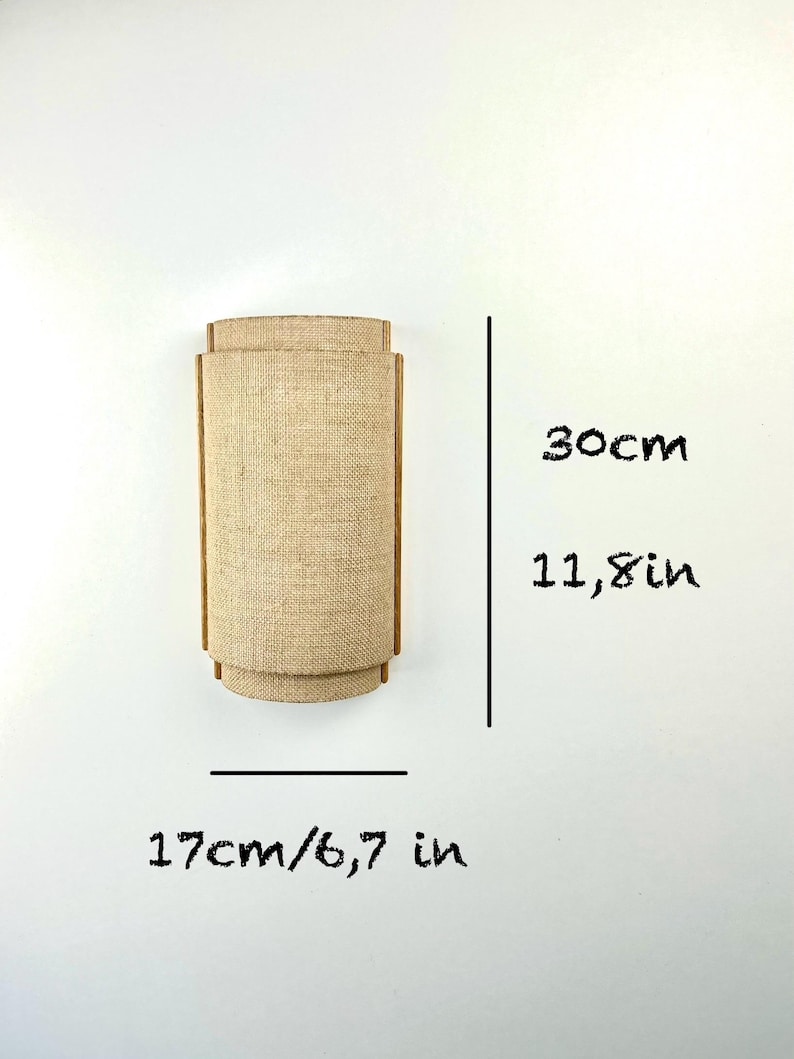 May include: A beige wall sconce with a woven fabric shade. The sconce measures 11.8 inches tall and 6.7 inches wide.