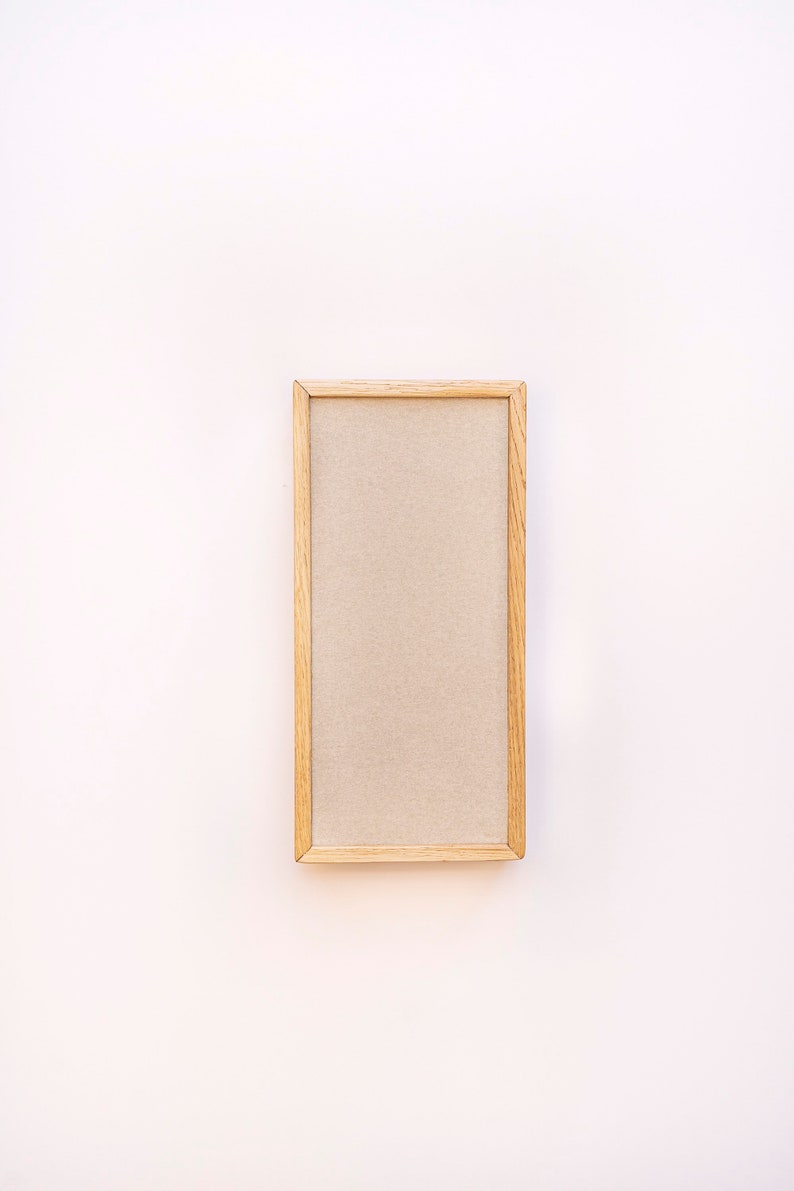 Pu&ograve; includere: Una cornice in legno semplice con un passepartout beige. La cornice &egrave; su uno sfondo bianco.