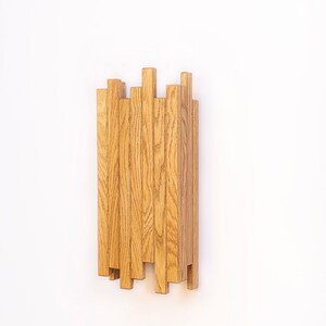 Peut inclure: Une &eacute;tag&egrave;re murale en bois au design unique. L'&eacute;tag&egrave;re est compos&eacute;e de multiples lattes de bois fines et verticales dispos&eacute;es en quinconce. Les lattes sont de couleur brun clair et pr&eacute;sentent un grain de bois naturel.