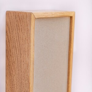 Pu&ograve; includere: Una cornice in legno con un passepartout beige chiaro. La cornice &egrave; in legno naturale con una venatura visibile.