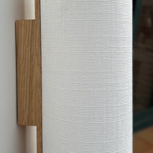 May include: A white fabric cylindrical lampshade attached to a wooden wall sconce.