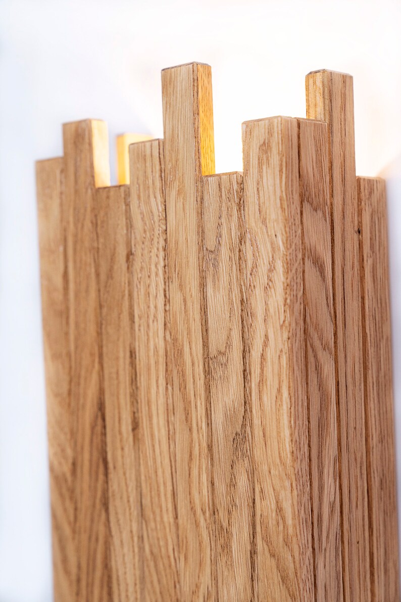 Peut inclure: Un luminaire mural en lattes de bois naturel. Le luminaire a un design moderne et minimaliste et est parfait pour ajouter une touche de chaleur et de texture &agrave; n'importe quelle pi&egrave;ce.
