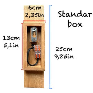 May include: A wooden electrical box with a standard size opening. The box is 9.8 inches wide and 5.1 inches tall. The box is 2.35 inches deep. The box is labeled "Standard box".