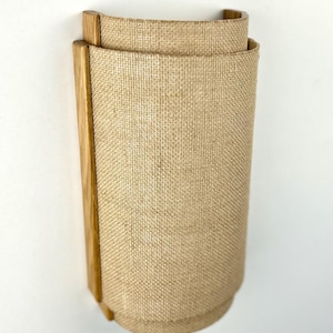 May include: A wall-mounted light fixture with a natural wood frame and a beige linen shade.