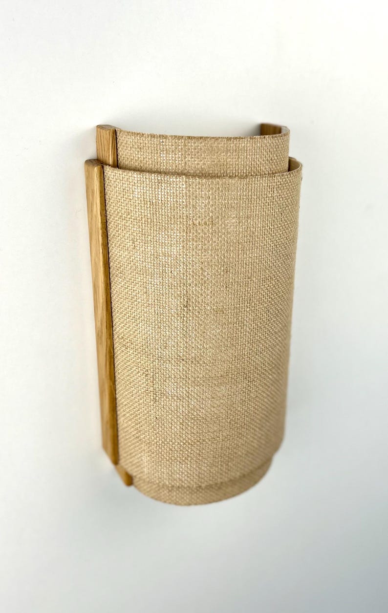 May include: A wall-mounted light fixture with a natural wood frame and a beige linen shade.