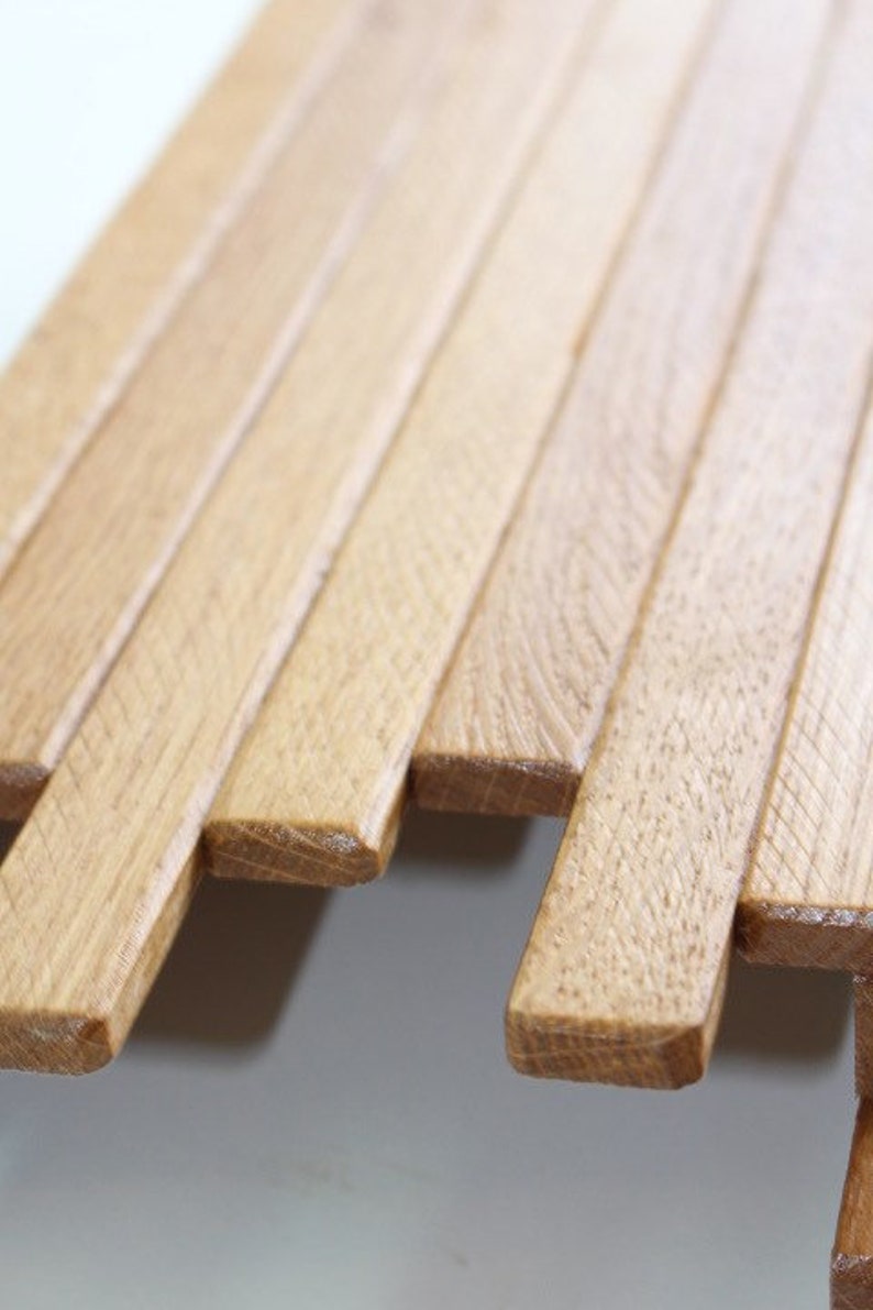 Peut inclure: Gros plan sur un panneau mural en lattes de bois. Les lattes sont dispos&eacute;es en quinconce, cr&eacute;ant une surface textur&eacute;e. Le bois est de couleur brun clair.