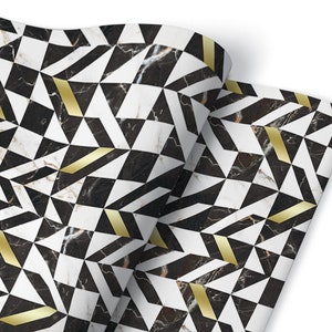 Op de afbeelding: Zwart-wit geometrisch patroon met gouden accenten op een marmeren achtergrond. Het patroon bestaat uit driehoeken en vierkanten.