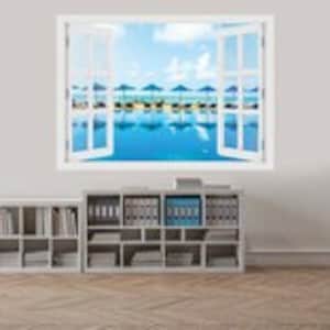 Puede incluir: Un marco de ventana blanco con vista a una escena de playa. La playa tiene tumbonas azules y sombrillas bajo un cielo azul brillante con nubes blancas.