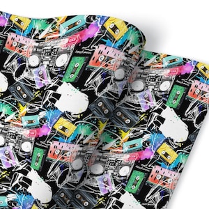 May include: A black and white wrapping paper design featuring colorful cassette tapes and boomboxes with splashes of paint. The design is reminiscent of 80s and 90s music.