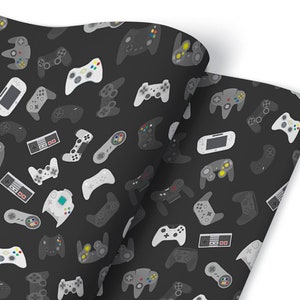 Könnte beinhalten: Schwarz-weißes Geschenkpapier mit einem sich wiederholenden Muster aus verschiedenen Videospielcontrollern. Die Controller sind in verschiedenen Stilen und Farben, darunter Grau, Weiß und Schwarz.