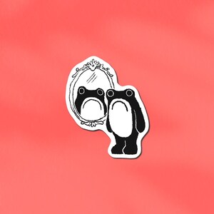 May include: A black and white sticker of a cartoon frog looking in a mirror. The mirror has an ornate frame, and the frog is standing. The background is a solid coral colour.
