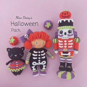 Może przedstawiać: Zestaw czterech szydełkowych zabawek na Halloween: dziewczynka w kostiumie szkieletu, czarny kot w pasiastym ubranku, łamacz orzechów z czaszką i mała dynia. Zabawki są ręcznie robione i mają fantazyjny, świąteczny wygląd.