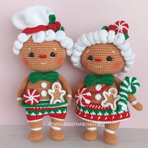 Puede incluir: Dos muñecos de jengibre de crochet con sombreros blancos, lazos verdes y detalles de bastón de caramelo. Los muñecos llevan pantalones y faldas a rayas rojas y verdes. Los muñecos están de pie sobre una superficie blanca. @missdaisyhandmade