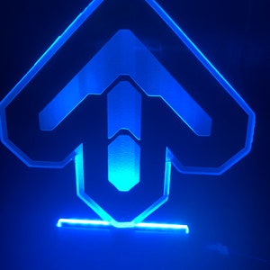 May include: A blue LED light shaped like an arrow pointing upwards. The light is on a black base.