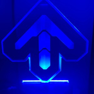 May include: A blue LED light shaped like an arrow pointing upwards. The light is on a black base.