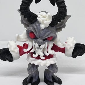 May include: A 3D-printed figurine of a Krampus-like creature. It has black horns, red eyes, and a gray face. The figure wears a red coat with white trim and black hooves. The creature has a menacing expression.