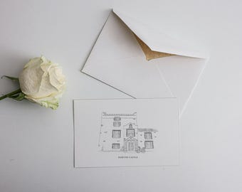 May include: A white rose and a card with a line drawing of Darter Castle are next to a white envelope. The envelope is open, showing a gold interior. The card is a detailed architectural illustration.
