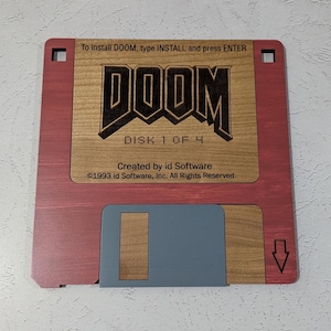 May include: A red and wood-grain floppy disk with a black DOOM logo and the text "DISK 1 OF 4" and "Created by id Software ©1993 id Software, Inc. All Rights Reserved."