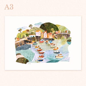 May include: A3 art print showing a coastal village scene with boats in a harbour. The illustration features colorful buildings, a bridge, and green hills. The artwork has a collage-like texture and a whimsical style.