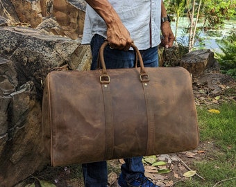 May include: A brown leather duffel bag with brass hardware. The bag has a top handle and a zipper closure.