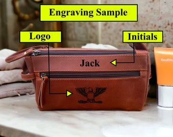 May include: Brown leather travel toiletry bag with a zipper closure. The bag is personalized with the name "Jack" and an eagle emblem.