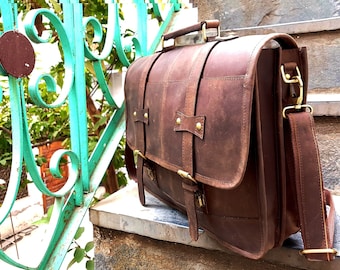 May include: A brown leather briefcase with a top handle and an adjustable shoulder strap. The bag has a flap closure with a buckle and multiple pockets.