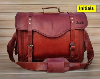 Puede incluir: Un maletín de cuero marrón con asa superior y bandolera. La bolsa tiene dos hebillas a cada lado y una solapa con una hebilla de latón. Las iniciales "Jack" están grabadas en la solapa.
