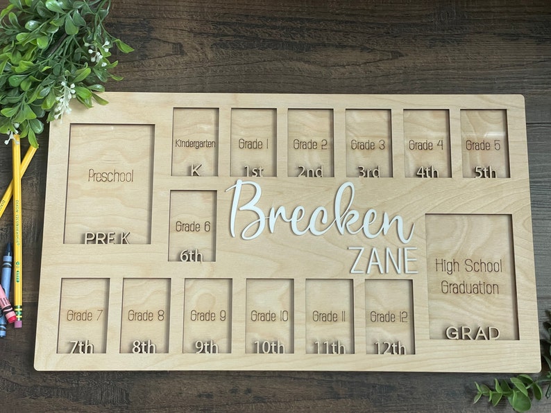 Puede incluir: Un marco de fotos de madera con ranuras para fotos de cada grado escolar, desde preescolar hasta la graduaci&oacute;n de la escuela secundaria. El marco est&aacute; personalizado con los nombres "Brecken Zane".
