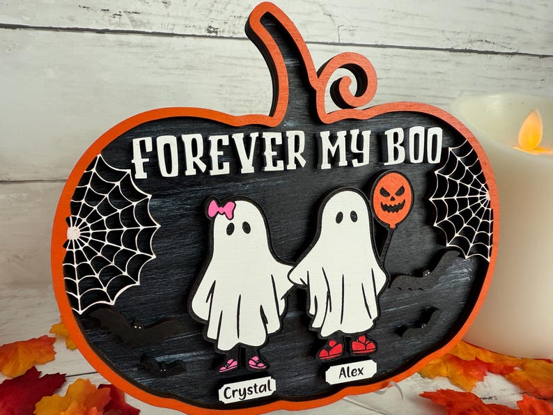 May include: A Halloween-themed wooden sign in the shape of a pumpkin. The sign features the phrase "FOREVER MY BOO" and two ghost figures holding hands. One ghost has a pink bow and the other holds a jack-o'-lantern balloon. The sign is decorated with spiderwebs and bats.