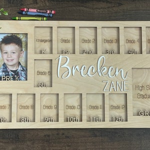 Puede incluir: Un marco de fotos de madera con ranuras para fotos de cada grado escolar, desde pre-K hasta la graduaci&oacute;n de la escuela secundaria. El marco est&aacute; personalizado con los nombres "Brecken Zane".