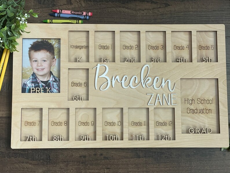 Puede incluir: Un marco de fotos de madera con ranuras para fotos de cada grado escolar, desde pre-K hasta la graduaci&oacute;n de la escuela secundaria. El marco est&aacute; personalizado con los nombres "Brecken Zane".