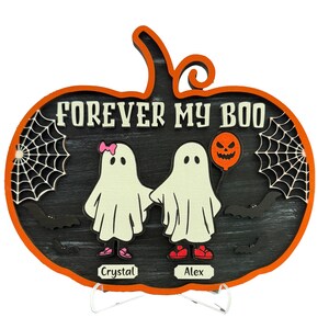 May include: A Halloween-themed wooden pumpkin decoration with the text "FOREVER MY BOO". It features two ghost figures holding hands, a jack-o'-lantern balloon, spiderwebs, and bats. The names "Crystal" and "Alex" are also included.