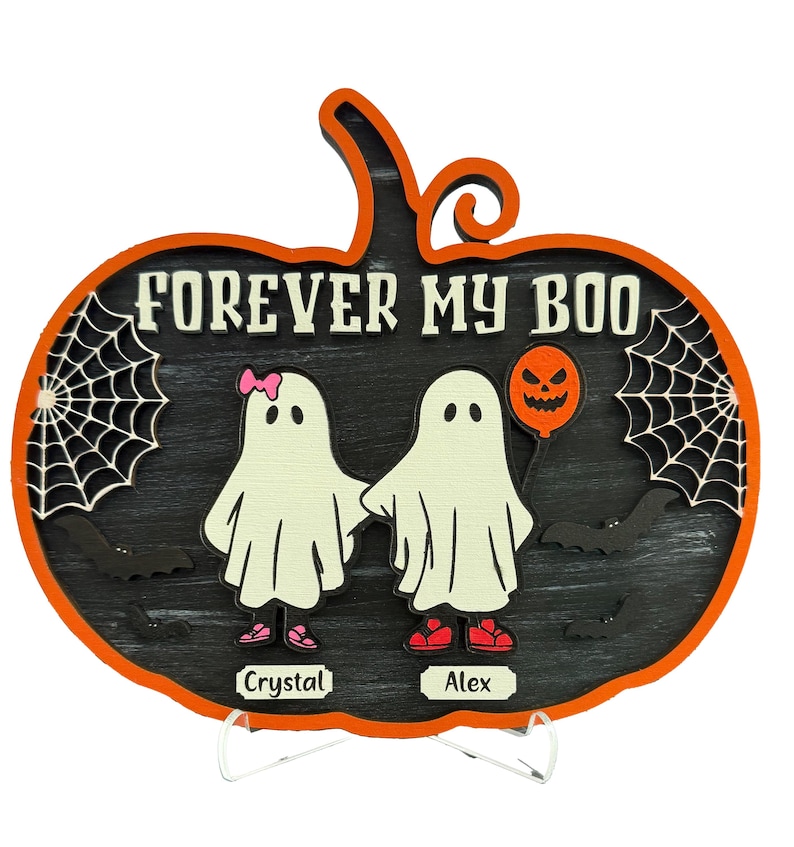 May include: A Halloween-themed wooden pumpkin decoration with the text "FOREVER MY BOO". It features two ghost figures holding hands, a jack-o'-lantern balloon, spiderwebs, and bats. The names "Crystal" and "Alex" are also included.